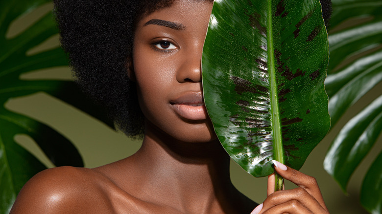 A woman holding a leaf in front of her face