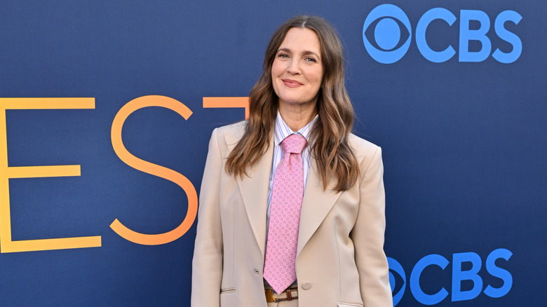 Drew Barrymore smiling while posing at an event in a suit
