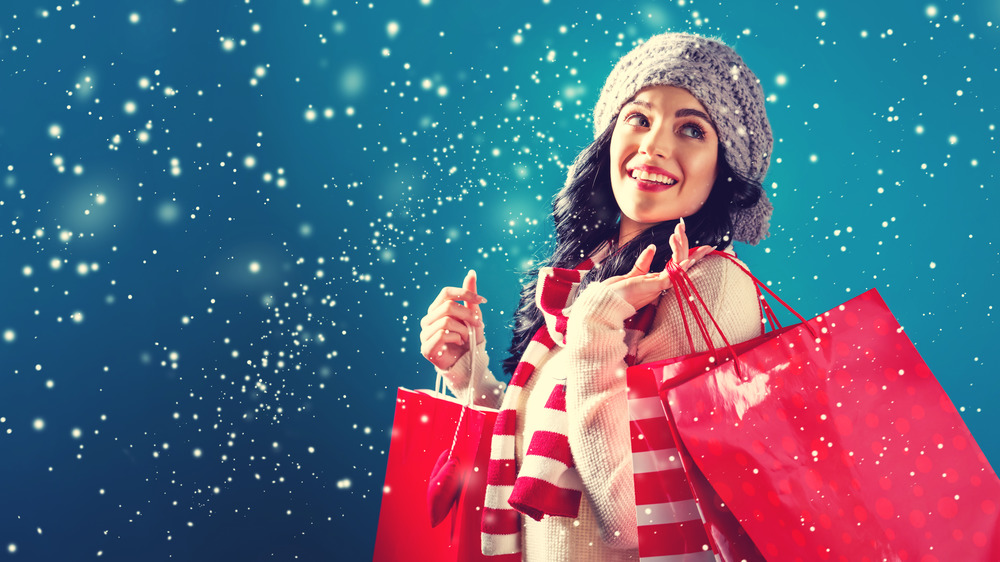 Woman dressed for the holidays carrying red shopping bags 