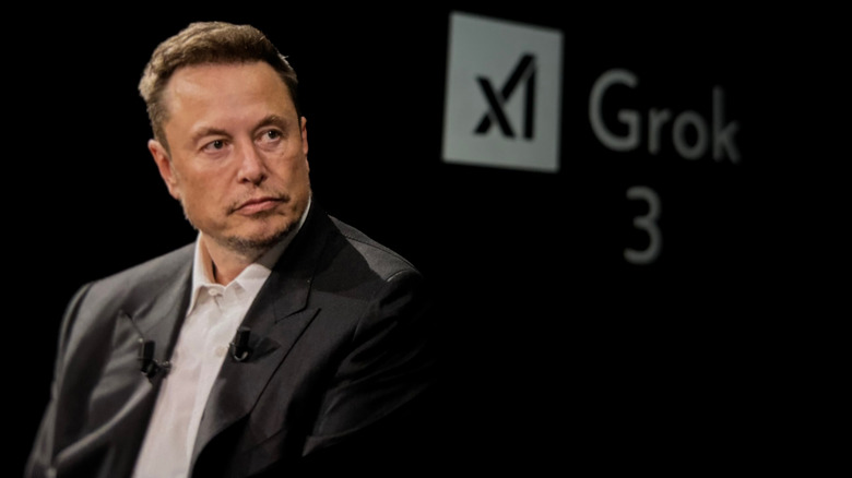 Elon Musk looking serious in a dark suit