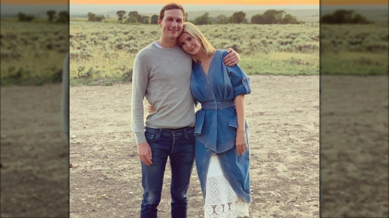 Ivanka Trump wearing a denim and lace dress and posing outdoors with Jared Kushner