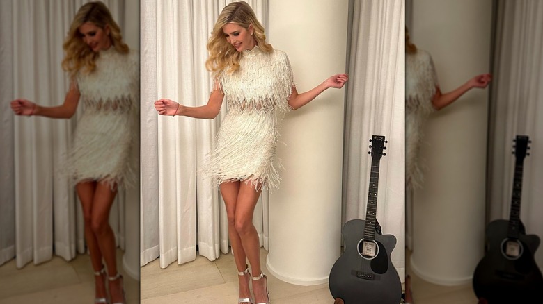 Ivanka Trump swaying her body in a white fringe dress and posing next to a black guitar