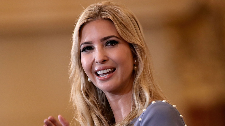 Ivanka Trump claps while standing at a microphone