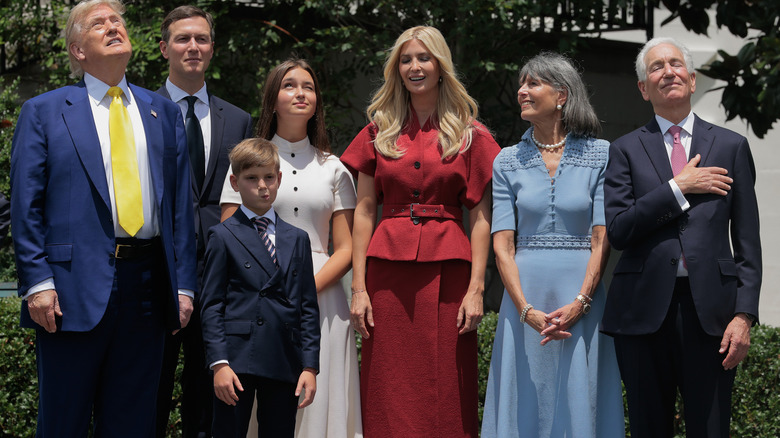 Ivanka Trump with eyes closed, wearing a red outfit standing outside with family members in various poses