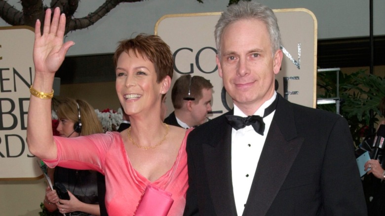 Jamie Lee Curtis waving while walking arm in arm with Christopher Guest.