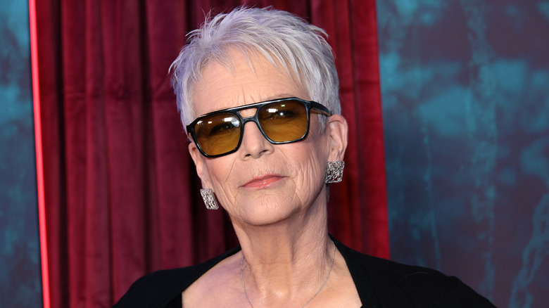 Jamie Lee Curtis posing on the red carpet while wearing sunglasses