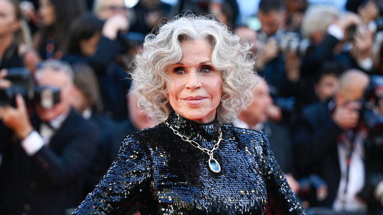 Jane Fonda in the foreground of a bunch of photographers wearing a black dress
