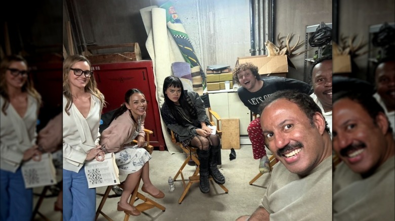 Janel Parrish sitting in a director's chair on the set of Stockholm Squad with castmates