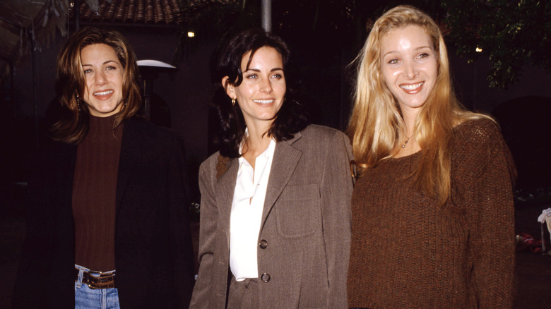 Jennifer Aniston, Courteney Cox, and Lisa Kudrow on the sidewalk.