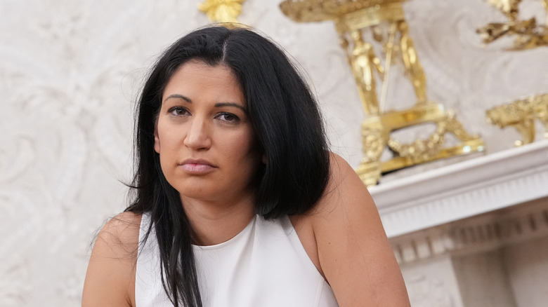 Katie Miller hunched over listening to President Trump and Elon Musk at the White House