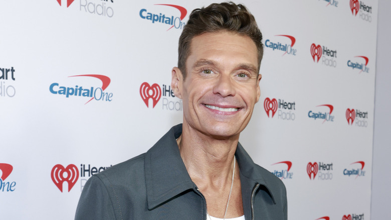 Ryan Seacrest wearing a white shirt under a gray jacket