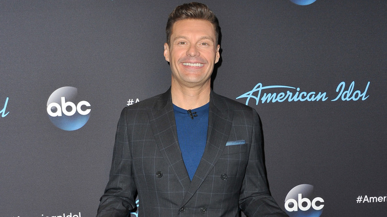 Ryan Seacrest wearing a black suit over a dark blue shirt