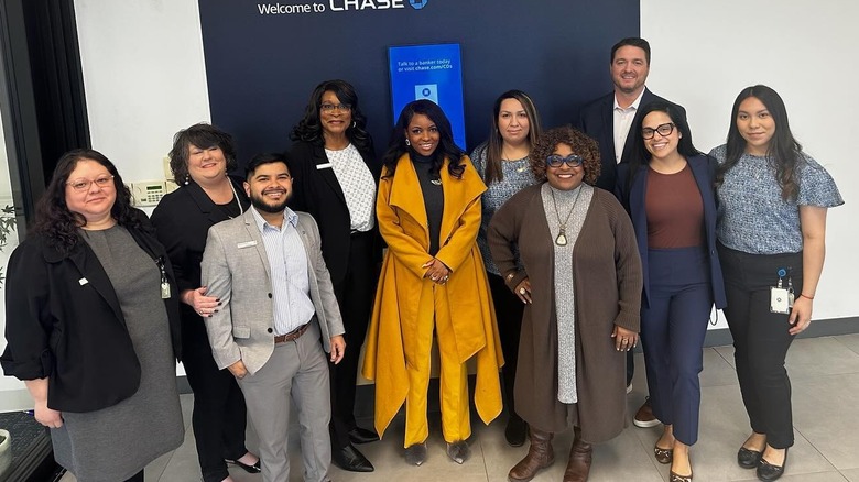 Jasmine Crockett standing beside the group of Chase Bank Community Center members under sign for Chase Bank.