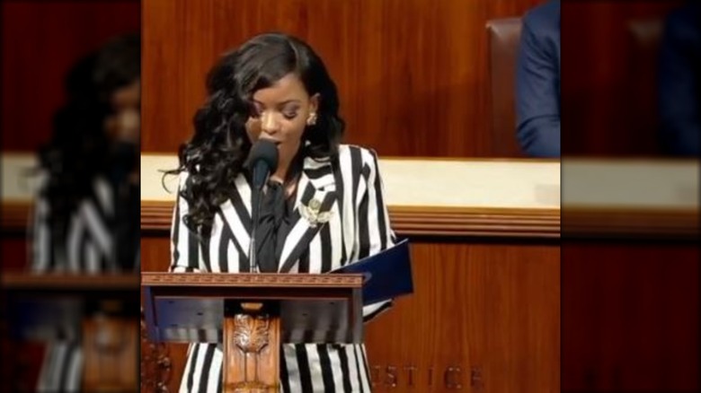Jasmine Crockett in a striped blazer behind a podium, talking.