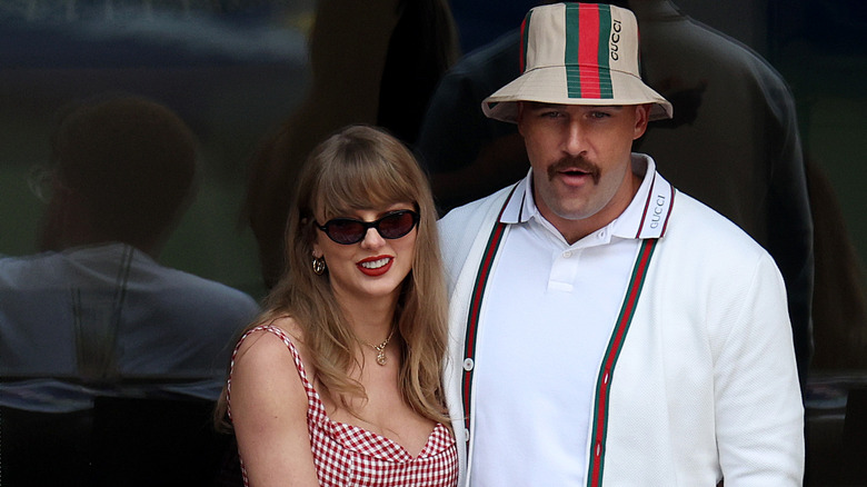 Taylor Swift and Travis Kelce standing together and smiling.