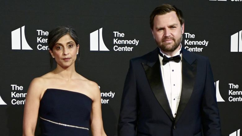Usha Vance wearing a black dress while holding the hand of JD Vance, who's in a suit, while they both pose at The Kennedy Center.