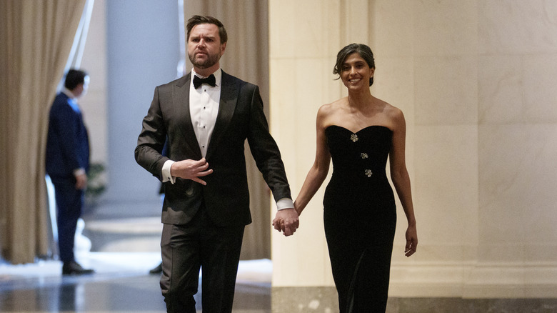 JD Vance wearing a suit and bowtie while holding Usha Vance's hand, who's in a black dress, as they walk together at the Vice Presidential dinner.