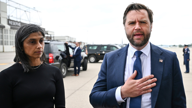 Usha Vance stares blankly while standing next to JD Vance as he speaks