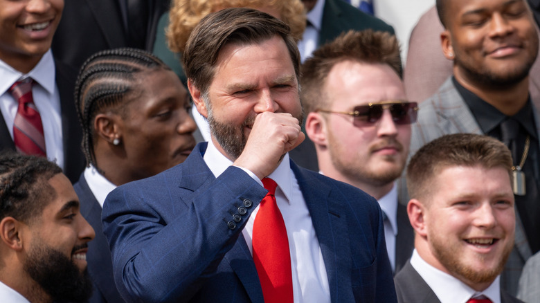 JD Vance laughing while holding his fist to his face