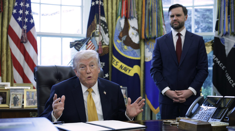 Donald Trump talking while JD Vance grimaces in the background