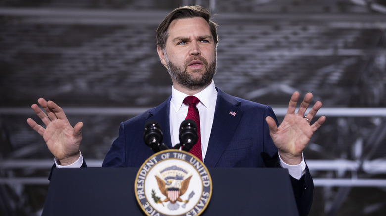 JD Vance speaking at a podium with his hands up in the air