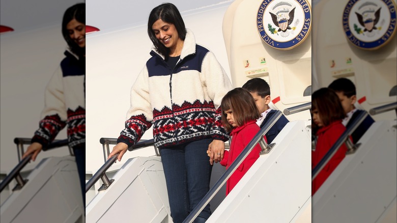 Usha Vance smiling and holding her daughter's hand while leaving Air Force One