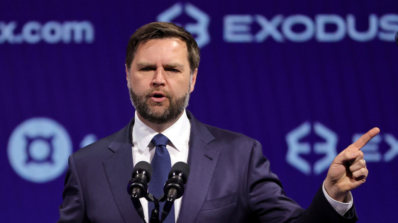 JD Vance stands at a podium and points