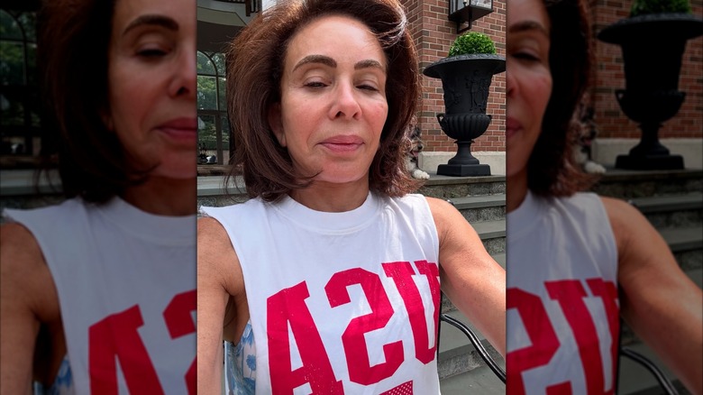 Judge Jeanine Pirro smirking while wearing a sleeveless white T-shirt.