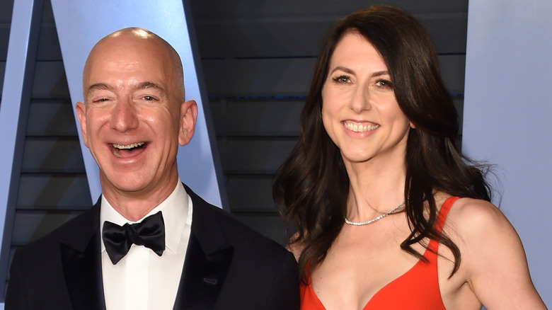 Jeff Bezos laughs in a tux beside a smiling MacKenzie Scott, who wears a red dress.