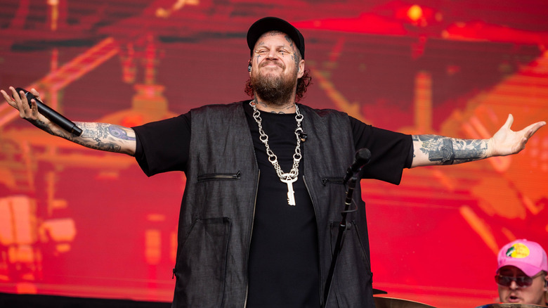 Jelly Roll spreading his arms onstage while wearing an all-black outfit