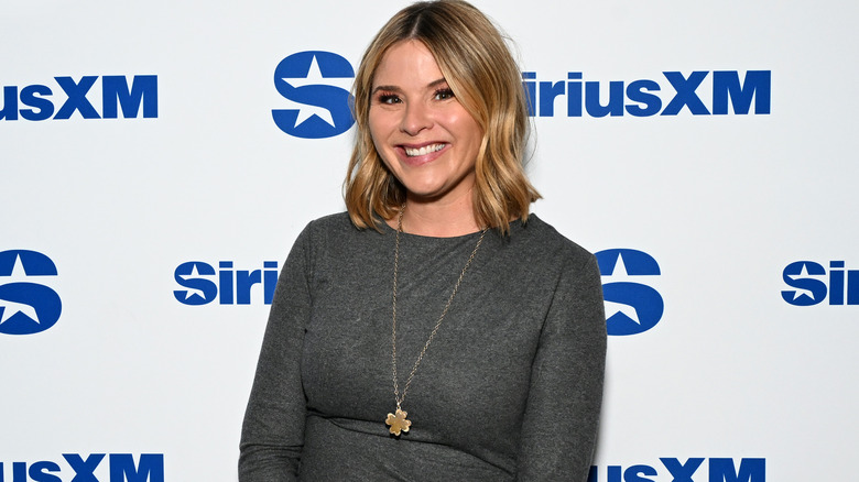 Jenna Bush Hager smiling while posing for photos in a grey, long-sleeved top