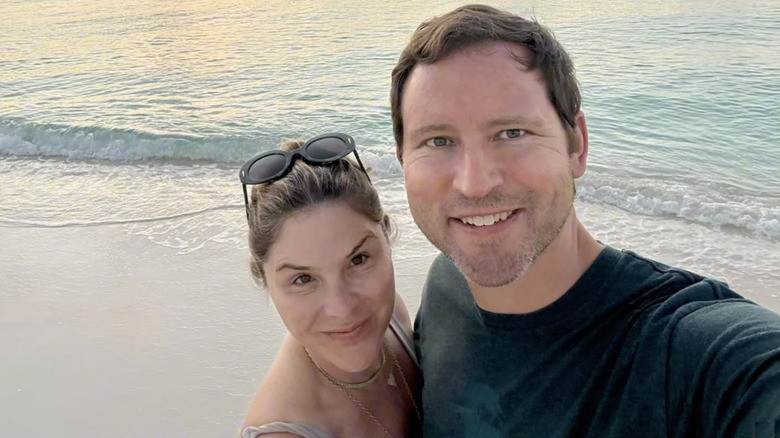 Jenna Bush Hager and husband Henry standing close together on the beach, ocean in the background, Jenna wearing no makeup