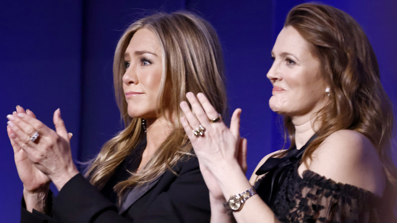Jennifer Aniston and Drew Barrymore clapping at event