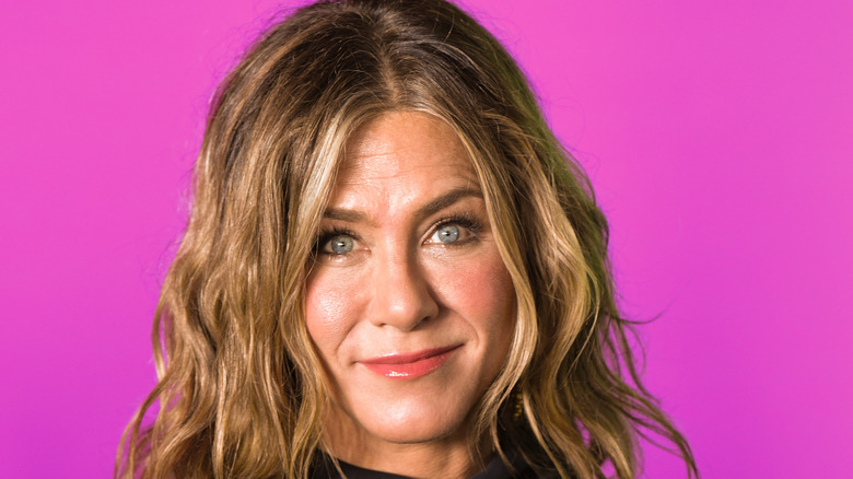 Jennifer Aniston smiling, pink background