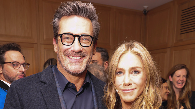 Jon Hamm smiling with Jennifer Aniston in a crowd