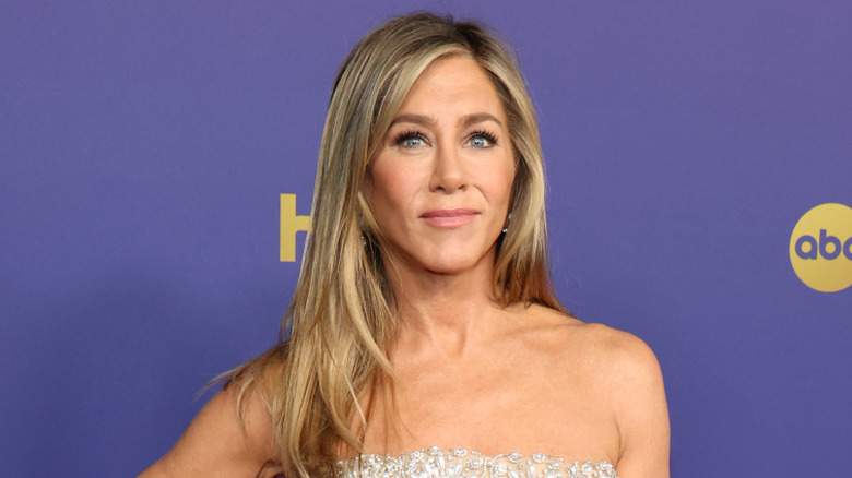 Jennifer Aniston posing in a strapless pearl beaded gown with hair down