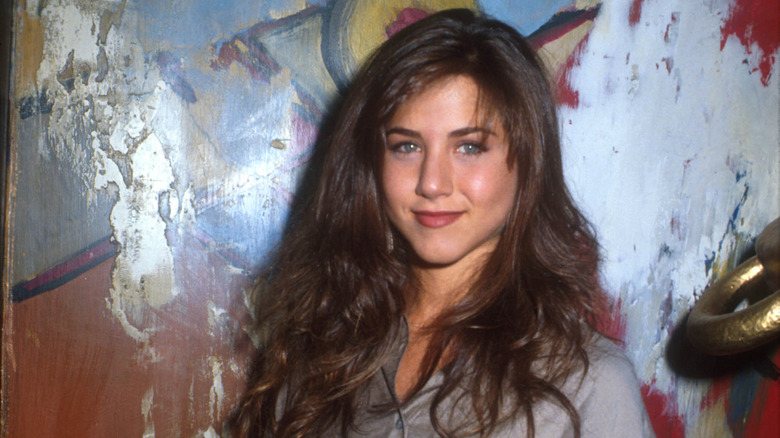 Young Jennifer Aniston in a gray shirt and brunette hair