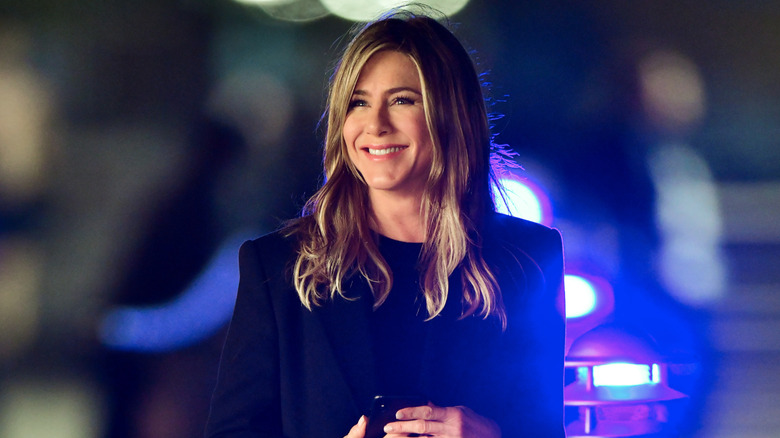 Jennifer Aniston smiling with neon lights in the background