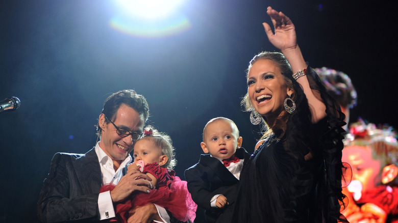Marc Anthony and Jennifer Lopez laughing and holding their twins on stage
