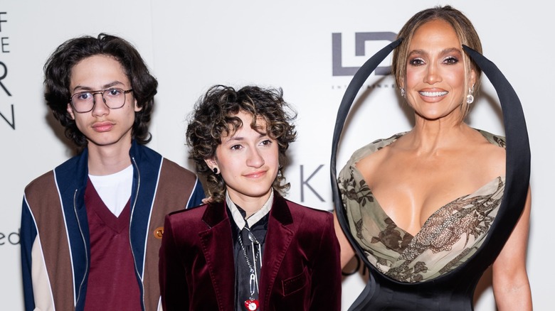 Jennifer Lopez smiling while posing with her twins, Max and Oskar, at a red carpet event