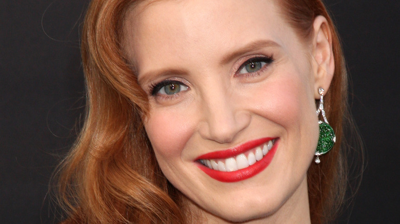 Jessica Chastain smiling for a picture while wearing red lipstick