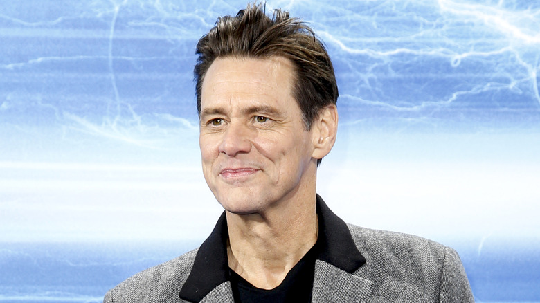 Jim Carrey posing for photos in a grey jacket