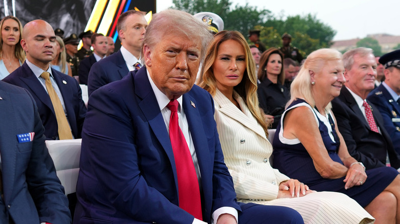 Donald and Melania Trump posing for cameras and seated in audience during military parade