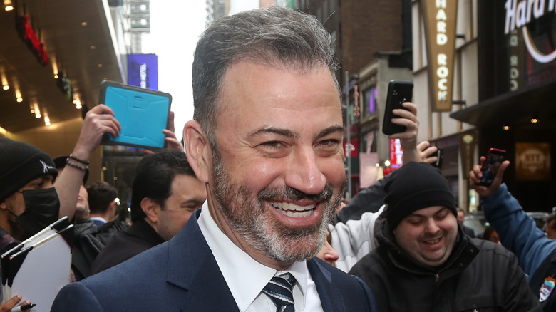 Closeup of Jimmy Kimmel smiling on street surrounded by fans taking pictures