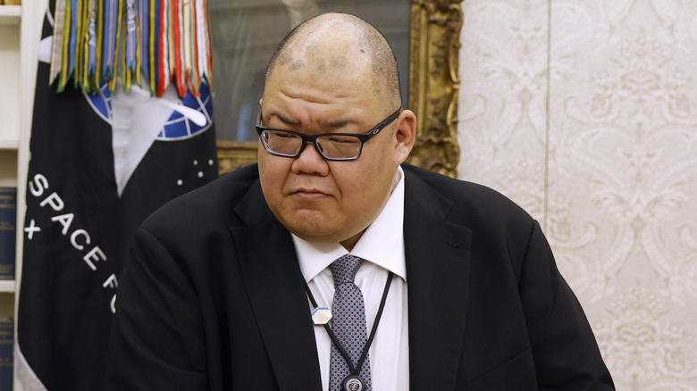 Steven Cheung looking dour in a black suit and glasses