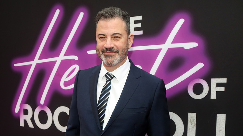 Jimmy Kimmel smiling while posing at an event in a dark suit