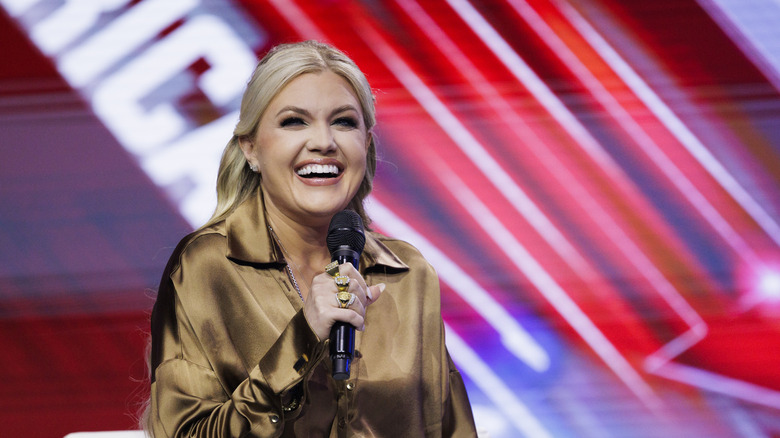 Erika Kirk smiling and holding a microphone