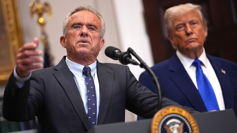 RFK Jr. speaking while Donald Trump stands behind him