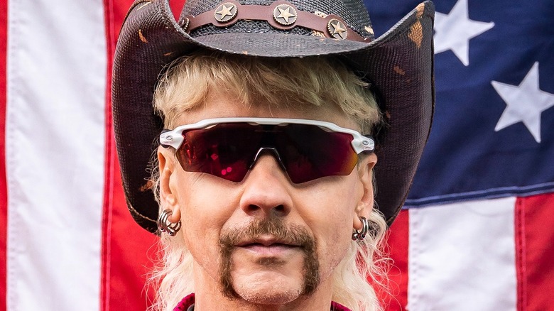 John Cameron Mitchell as Joe Exotic in front of a flag