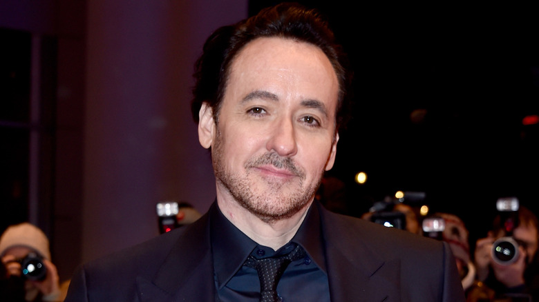 John Cusack smirking and looking straight into the camera